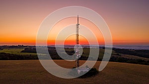 Aerial view of a broadcast tower on top of a hill at a colorful sunset