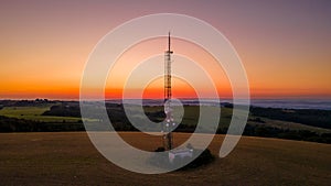 Aerial view of a broadcast tower on top of a hill at a colorful sunset