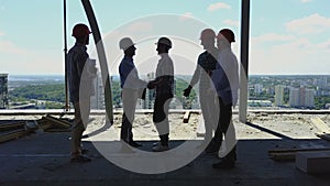 Aerial view of builders team handshake with business man employer on construction site, meeting of group of contractors