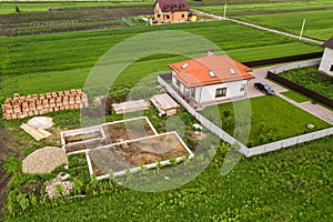 Aerial view of building site for future brick house, concrete foundation floor and stacks of yellow clay bricks for construction