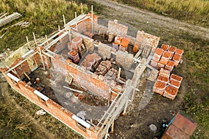 Aerial view of building site for future brick house, concrete foundation floor and stacks of yellow clay bricks for construction