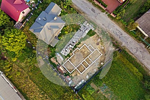 Aerial view of building site for future brick house, concrete foundation floor and stacks of yellow clay bricks for construction
