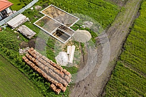 Aerial view of building site for future brick house, concrete foundation floor and stacks of yellow clay bricks for construction