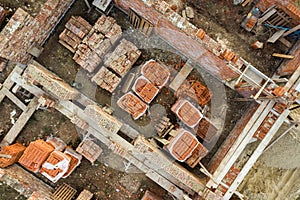 Aerial view of building site for future brick house, concrete foundation floor and stacks of yellow clay bricks for construction