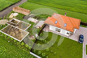 Aerial view of building site for future brick house, concrete foundation floor and stacks of yellow clay bricks for construction