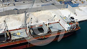 Aerial view of bulk-carrier ship docked loading minerals in port.