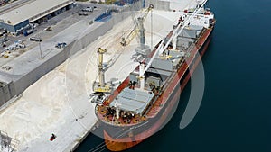 Aerial view of bulk-carrier ship docked loading minerals in port.