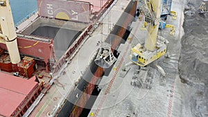 Aerial view of bulk-carrier ship docked loading minerals in port.