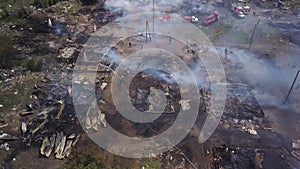 Aerial view of burned houses in village, firefighters are extinguishing fire