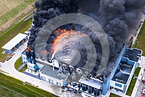 Aerial view of burnt industrial warehouse or logistics center building after big fire with huge smoke from burned roof