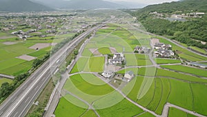 Aerial view of bus and light traffic on highway through rural rice fields