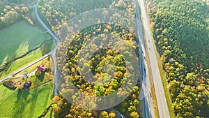 Aerial view of busy american highway with fast moving traffic surrounded by fall forest trees. Interstate transportation