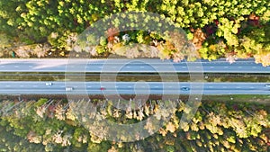 Aerial view of busy american highway with fast moving traffic surrounded by fall forest trees. Interstate transportation