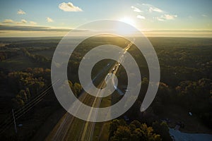 Aerial view of busy american highway with fast moving traffic surrounded by fall forest trees. Interstate transportation