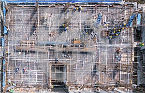 Aerial view of busy industrial construction site workers with cranes working. Top view of development high rise architecture