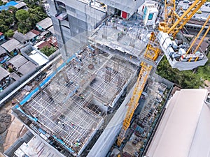 Aerial view of busy industrial construction site workers with cranes working. Top view of development high rise architecture