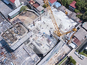 Aerial view of busy industrial construction site workers with cranes working. Top view of development high rise architecture