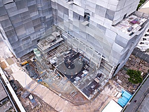 Aerial view of busy industrial construction site workers with cranes working. Top view of development high rise architecture