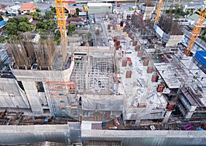 Aerial view of busy industrial construction site workers with cranes working. Top view of development high rise architecture