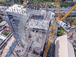 Aerial view of busy industrial construction site workers with cranes working. Top view of development high rise architecture