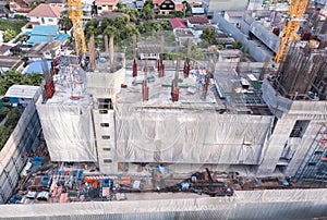 Aerial view of busy industrial construction site workers with cranes working. Top view of development high rise architecture