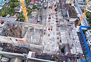 Aerial view of busy industrial construction site workers with cranes working. Top view of development high rise architecture