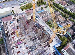 Aerial view of busy industrial construction site workers with cranes working. Top view of development high rise architecture