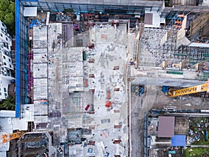 Aerial view of busy industrial construction site workers with cranes working. Top view of development high rise architecture