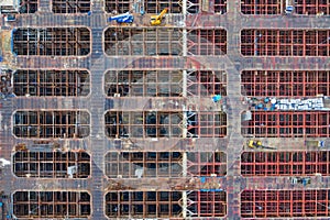 Aerial view of busy industrial under construction site workers working with cranes and excavators. Top view of precast concrete