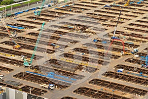 Aerial view of busy industrial under construction site workers working with cranes and excavators. Top view of precast concrete