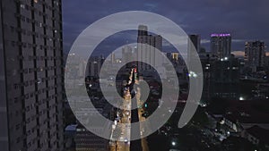 Aerial view of busy multilane street in night city. Rising shot revealing evening cityscape. Manila, Philippines