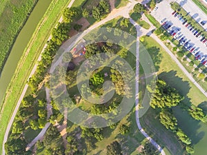 Aerial view busy parking lots at trailhead of urban park with playground, pathway in Houston