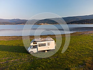 Aerial view of a camper van parked on a beach, mountain range landscape