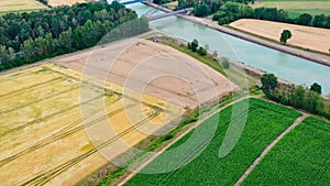 Aerial view of a canal that runs through fields, meadows and arable land in the flat landscape of northern Germany