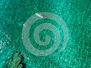 Aerial view of a canoe in the water floating on a transparent sea. Bathers at sea. Zambrone, Calabria, Italy