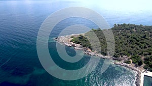 Aerial view of cape with trees and speedboats in stunning blue sea, Pefkohori Halkidiki, Greece, moving forward by drone