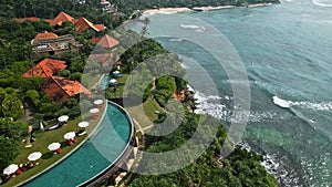 Aerial view captures luxury resort nestled tropical landscape, oceanfront villas terracotta roofs, infinity pool edges