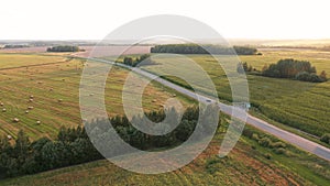 Aerial View Car Drives Along Country Road Through Rural Fields At Sunset