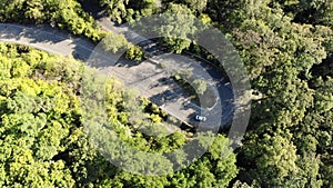 Aerial view of car driving on country road in forest. Cinematic drone shot flying. Nature, travel, holidays. 4K motion