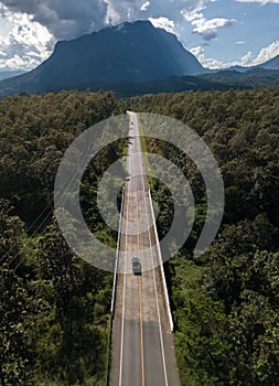 Aerial view of car driving on the highway road leading to Doi Luang Chiang Dao mountain in Chiang Mai province of Thailand.