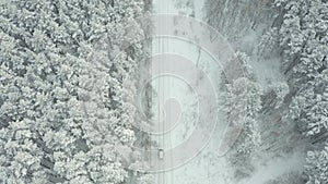 Aerial view on car driving through winter forest road. Scenic winter landscape.