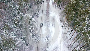 Aerial view of the car moving in the winter forest.