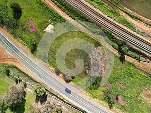 Aerial view of car on Northam-Toodyay highway and railway with pink wildflowers Western Australia