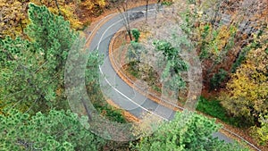 Aerial view of car passing curvy road in forest. Autumn high in mountains