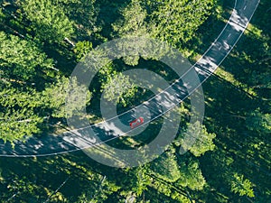 Aerial view of car with a roof rack on a country road and green woods in Finland