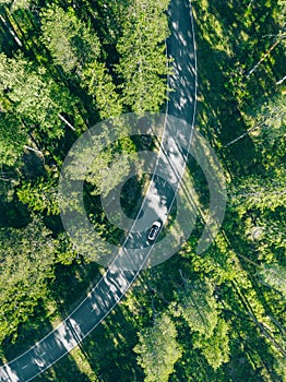 Aerial view of car with a roof rack on a country road and green woods in Finland