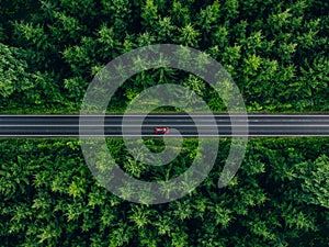Aerial view of car with a roof rack on a country road and green woods in Finland