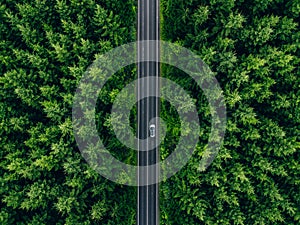 Aerial view of car with a roof rack on a country road and green woods in Finland