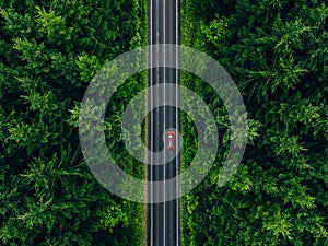 Aerial view of car with a roof rack on a country road and green woods in Finland