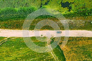 Aerial View Of Car SUV Parked On Countryside Road Between Rural Field And Marsh Bog Swamp Landscape. Summer Day